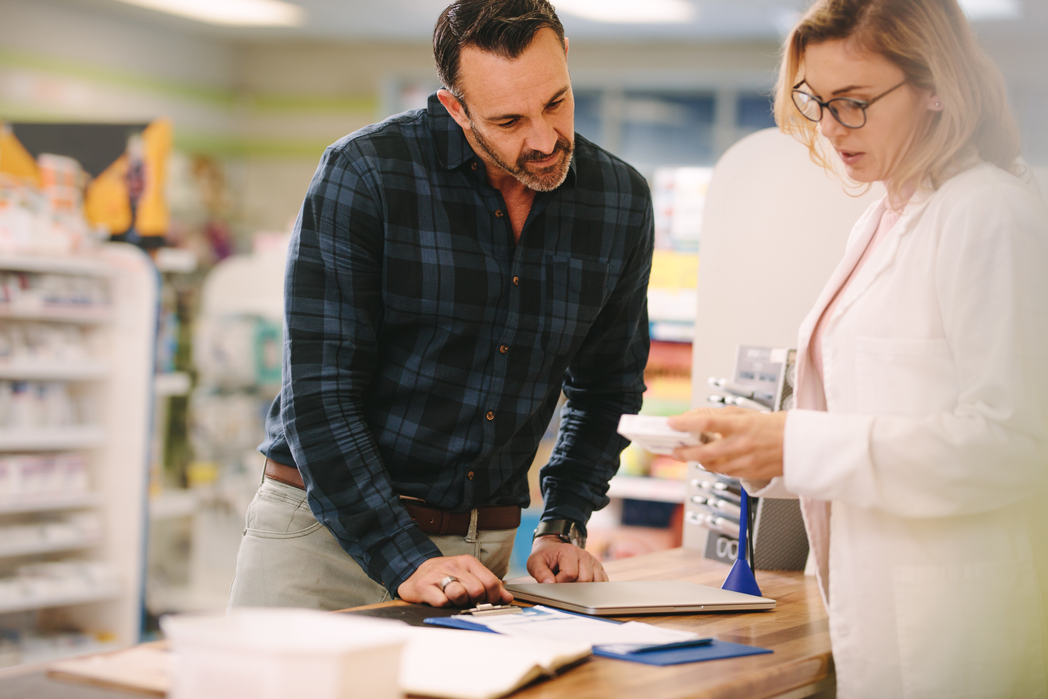 Pharmacist showing medicine to customer in independent pharmacy